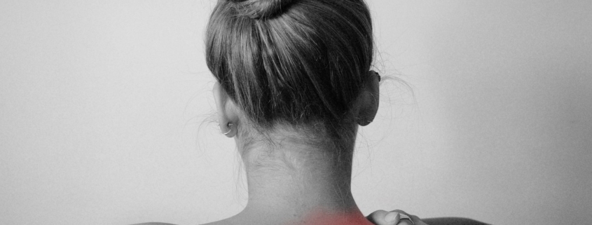 Woman holding the top of her shoulder and neck where it hurts