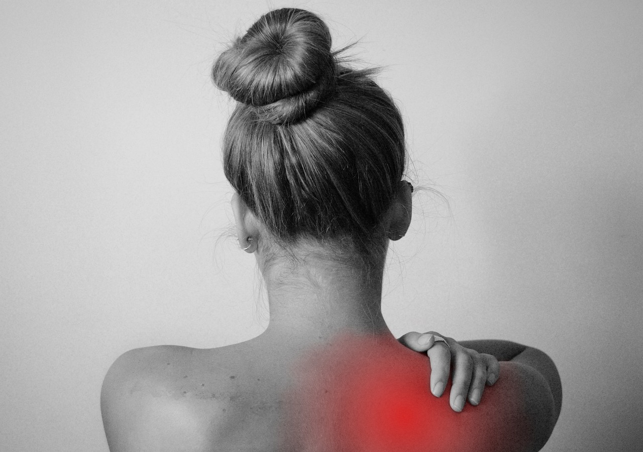 Woman holding the top of her shoulder and neck where it hurts