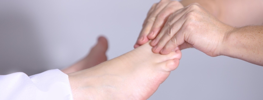 Practitioner massaging a patient's bare foot during treatment