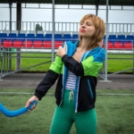 Woman holding her sore shoulder at an outdoor sports field