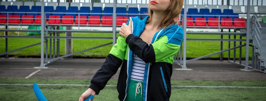 Woman holding her sore shoulder at an outdoor sports field